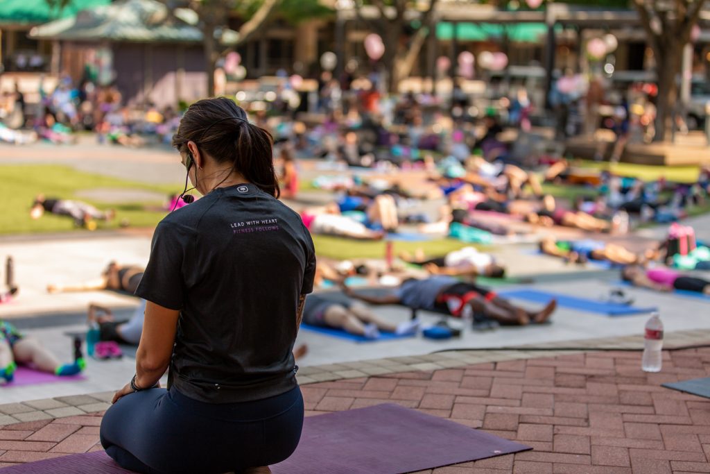 A Bloom instructor leads hundreds of participants at an outdoor community fitness event